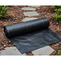 Roll of black landscape fabric with green grid lines on a yard  background